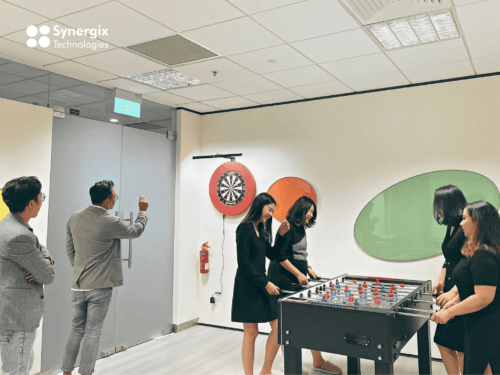 Employees enjoying recreational activities including foosball and darts in a modern office break room.